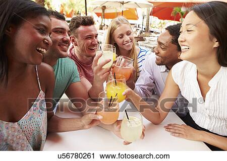 Stock Image - Group Of Friends Enjoying Drinks In Outdoor Restaurant. Fotosearch