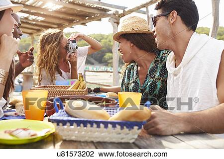 Stock Image - Group Of Friends Enjoying Lunch And Taking Photographs . Fotosearch