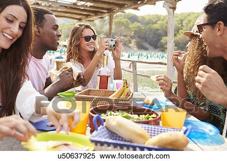 Stock Photography - Group Of Friends Enjoying Lunch And Taking Photographs . Fotosearch