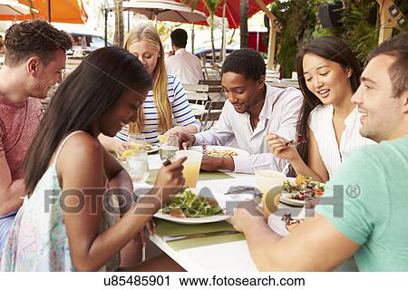 Stock Image - Group Of Friends Enjoying Lunch In Outdoor Restaurant. Fotosearch