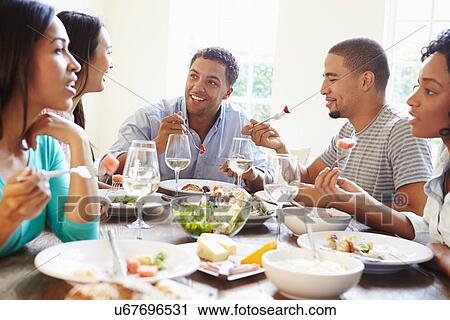 Stock Image - Group Of Friends Enjoying Meal At Home Together. Fotosearch