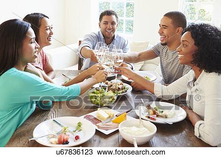 Stock Image - Group Of Friends Enjoying Meal At Home Together. Fotosearch