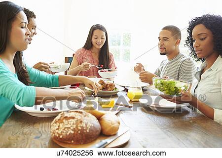 Stock Photograph - Group Of Friends Enjoying Meal At Home Together. Fotosearch