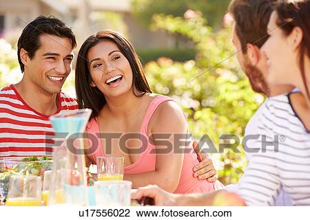 Stock Image - Group Of Friends Enjoying Meal At Outdoor Party In Back Yard. Fotosearch