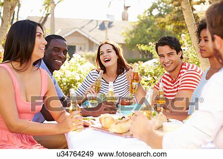 Stock Photo - Group Of Friends Enjoying Meal At Outdoor Party In Back Yard. Fotosearch