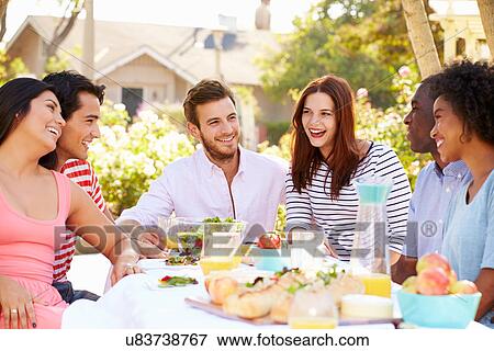 Stock Photo - Group Of Friends Enjoying Meal At Outdoor Party In Back Yard. Fotosearch