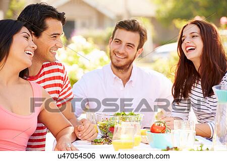 Stock Photograph - Group Of Friends Enjoying Meal At Outdoor Party In Back Yard. Fotosearch