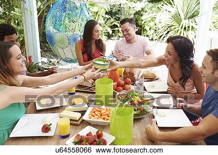 Stock Photograph - Group Of Friends Enjoying Meal Outdoors At Home. Fotosearch