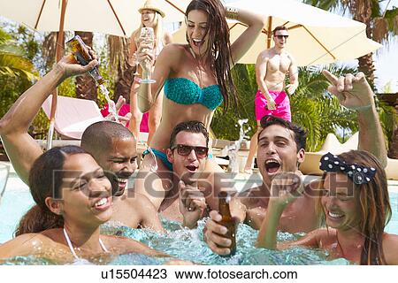Stock Image - Group Of Friends Having Party In Pool Drinking Champagne. Fotosearch
