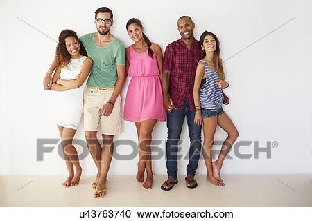 Stock Image - Group Of Friends Leaning Against White Wall. Fotosearch
