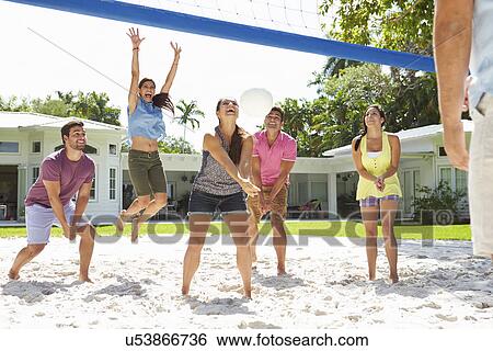 Stock Photograph - Group Of Friends Playing Volleyball In Garden . Fotosearch
