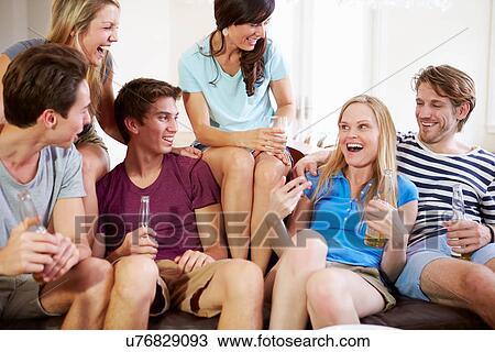 Stock Image - Group Of Friends Relaxing On Sofa At Home Together. Fotosearch
