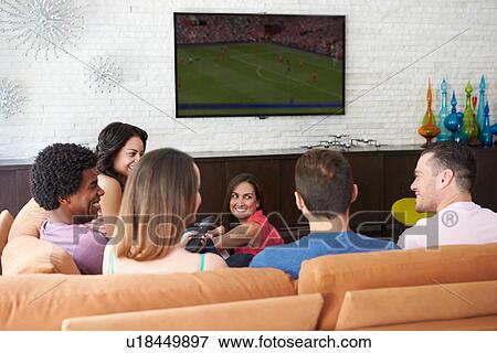 Stock Photo - Group Of Friends Sitting On Sofa Watching Soccer Together. Fotosearch