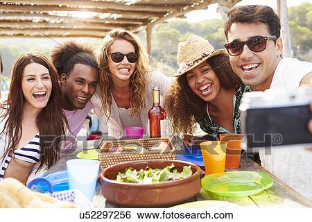 Stock Photograph - Group Of Friends Taking Selfie During Lunch Outdoors. Fotosearch