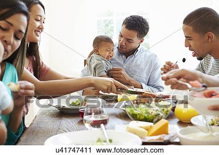 Stock Image - Group Of Friends With Babies Enjoying Meal At Home Together. Fotosearch