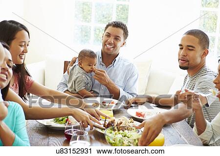 Stock Image - Group Of Friends With Babies Enjoying Meal At Home Together. Fotosearch
