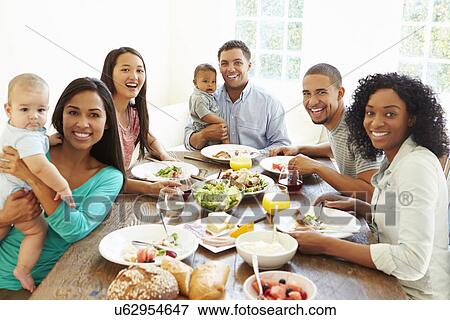 Stock Photo - Group Of Friends With Babies Enjoying Meal At Home Together. Fotosearch
