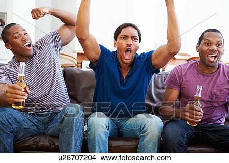 Group Of Men Sitting On Sofa Watching TV Together View Large Photo Image Picture - Group Of Men Sitting On Sofa Watching TV Together. Fotosearch