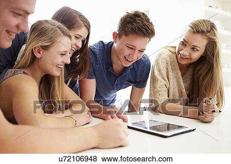 Stock Photo - Group Of Teenagers Gathered Around Digital Tablet Together. Fotosearch