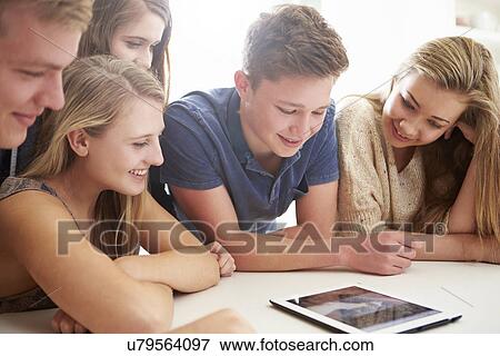 Group Of Teenagers Gathered Around Digital Tablet Together View Large Photo Image Stock Photo - Group Of Teenagers Gathered Around Digital Tablet Together. Fotosearch