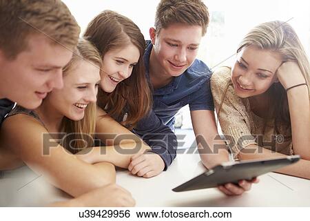 Stock Photograph - Group Of Teenagers Gathered Around Digital Tablet Together. Fotosearch