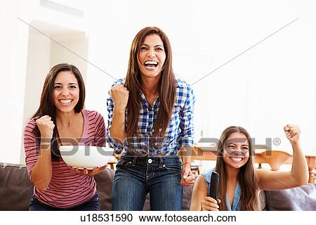 Stock Image - Group Of Women Sitting On Sofa Watching Sport Together. Fotosearch