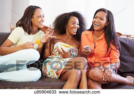 Stock Image - Group Of Women Sitting On Sofa Watching TV Together. Fotosearch