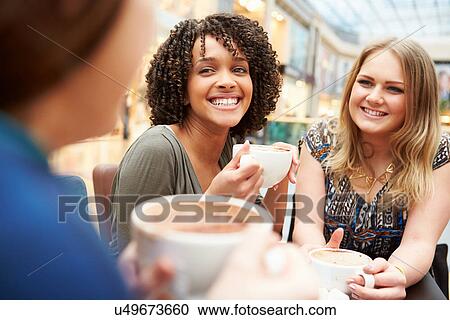 Stock Image - Group Of Young Female Friends Meeting In Cafe. Fotosearch