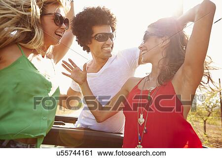 Stock Image - Group Of Young Friends Dancing In Back Of Open Top Car. Fotosearch