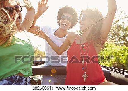 Stock Image - Group Of Young Friends Dancing In Back Of Open Top Car. Fotosearch