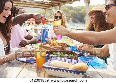 Group Of Young Friends Enjoying Lunch Outdoors View Large Photo Image Stock Photo - Group Of Young Friends Enjoying Lunch Outdoors. Fotosearch