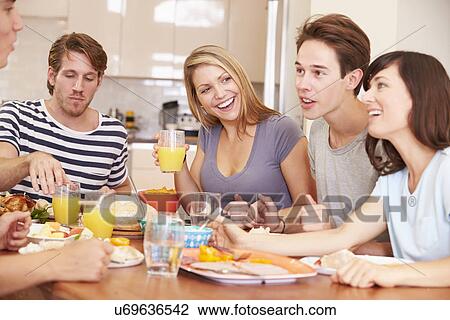 Stock Image - Group Of Young Friends Enjoying Meal At Home. Fotosearch