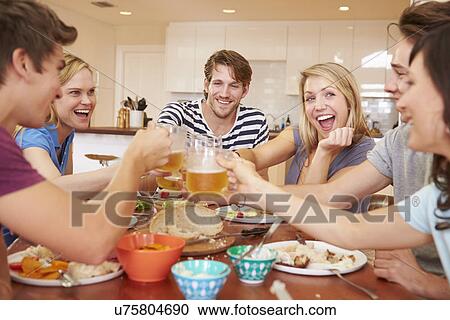 Stock Image - Group Of Young Friends Enjoying Meal At Home. Fotosearch