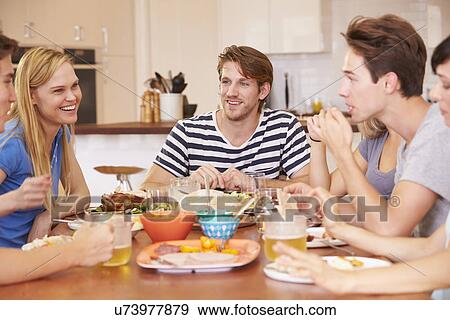 Stock Photo - Group Of Young Friends Enjoying Meal At Home. Fotosearch