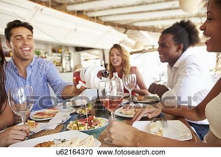 Group Of Young Friends Enjoying Meal In Outdoor Restaurant View Large Photo Image Stock Image - Group Of Young Friends Enjoying Meal In Outdoor Restaurant. Fotosearch
