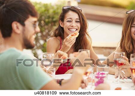 Stock Photo - Group Of Young Friends Enjoying Meal In Outdoor Restaurant. Fotosearch