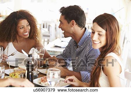 Stock Photo - Group Of Young Friends Enjoying Meal In Outdoor Restaurant. Fotosearch