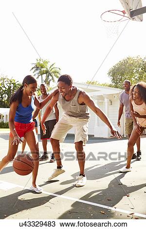 Stock Image - Group Of Young Friends Playing Basketball Match. Fotosearch