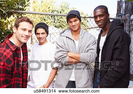 Picture - Group Of Young Men In Urban Setting Standing By Fence. Fotosearch