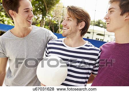 Stock Photo - Group Of Young Men Playing Volleyball Match. Fotosearch