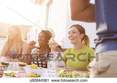 Stock Image - Group Of Young People Enjoying Outdoor Summer Meal. Fotosearch