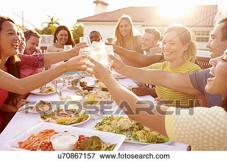Stock Photo - Group Of Young People Enjoying Outdoor Summer Meal. Fotosearch