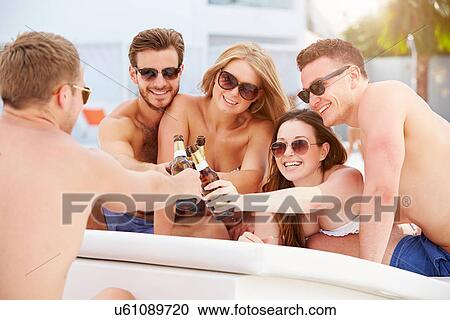Stock Image - Group Of Young People On Holiday Relaxing By Swimming Pool. Fotosearch