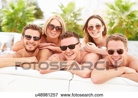 Stock Photo - Group Of Young People On Holiday Relaxing By Swimming Pool. Fotosearch