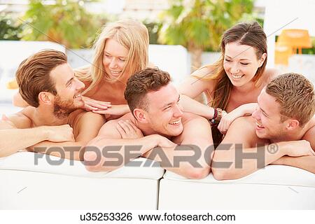 Stock Photograph - Group Of Young People On Holiday Relaxing By Swimming Pool. Fotosearch