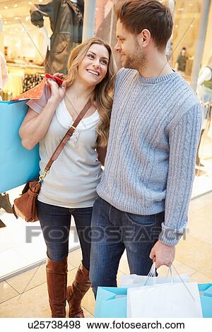 Stock Photo - Happy Couple Carrying Bags In Shopping Mall. Fotosearch