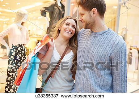 Happy Couple Carrying Bags In Shopping Mall View Large Photo Image Stock Photo - Happy Couple Carrying Bags In Shopping Mall. Fotosearch