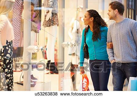 Stock Photo - Happy Couple Carrying Bags In Shopping Mall. Fotosearch