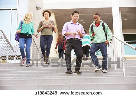 Stock Photo - High School Pupils And Teacher On Steps Outside Building. Fotosearch