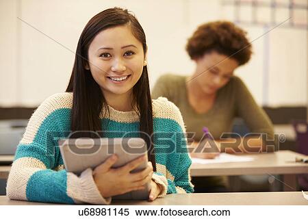 Stock Photography - High School Student At Desk In Class Using Digital Tablet. Fotosearch